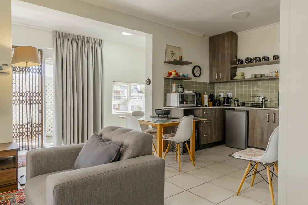 A bright self catering apartment with a lounge chair and open plan kitchen