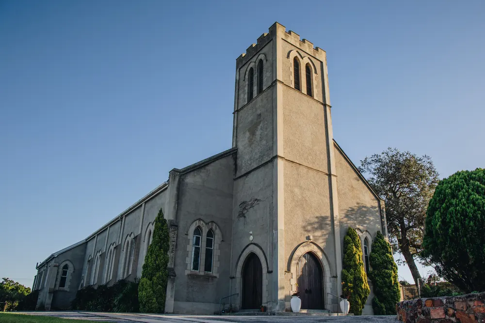 A stone church with a square bell tower under a clear blue sky